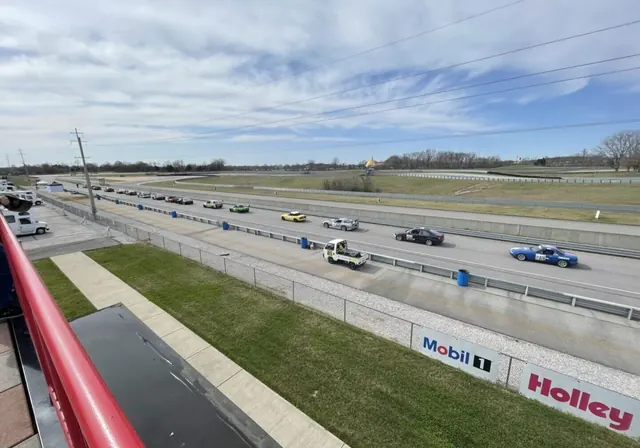 View down a drag strip from the stands as cars line up at the start