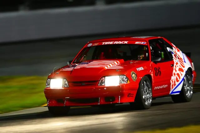 The red Laps of Honor Fox-body Mustang on track at night, headlights on