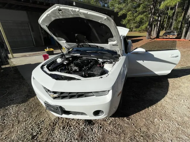 The white T1 Camaro with its hood and doors open
