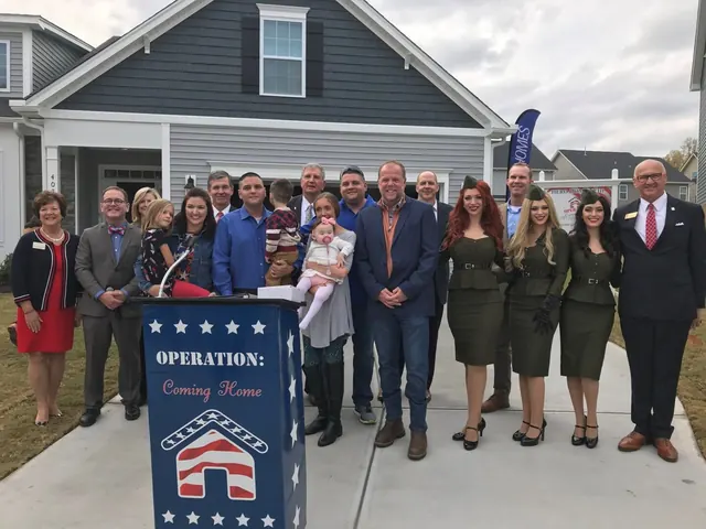 Group gathered in front of a new home behind an Operation: Coming Home podium