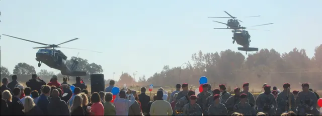 Crowd watching as helicopters fly over an outdoor event